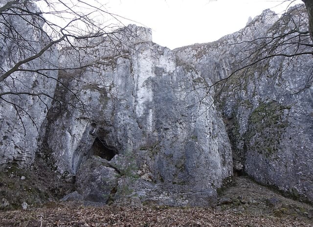Skały i otwór zespołu Jaskini Wierzchowskiej Górnej, marzec 2022. Fotografia archiwalna, bez potwierdzenia obecnej dostępności wnętrza.
