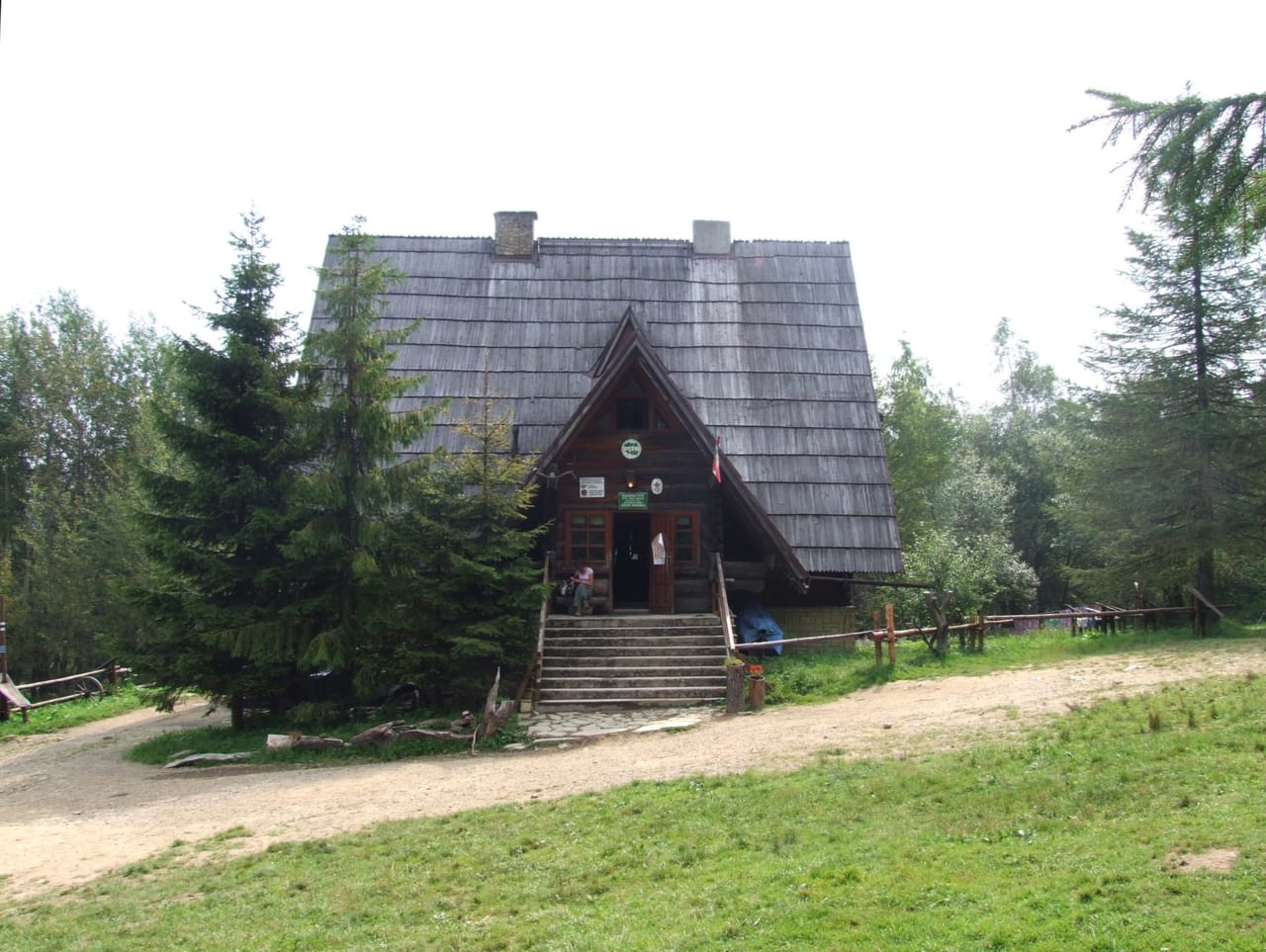 Drewniana Bacówka pod Małą Rawką ze schodami i gankiem na tle lasu